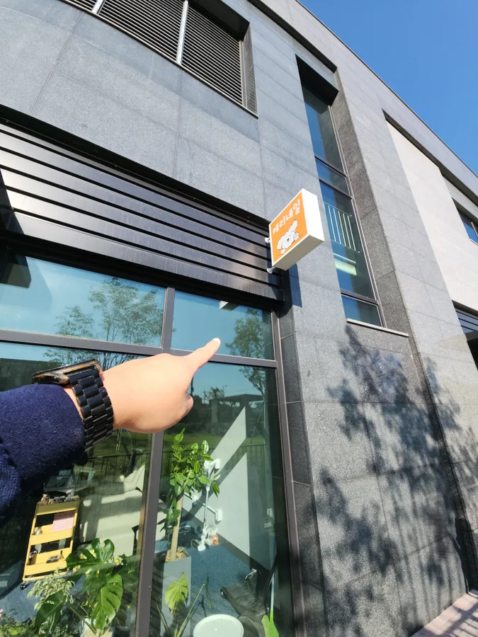 상가 외벽 간판 아래 유리를 손가락으로 가리키는 모습