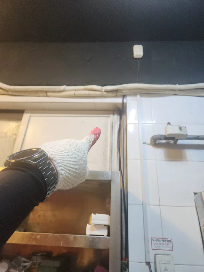 주방 벽 위쪽 환기 구멍 위치를 손가락으로 가리키는 모습
