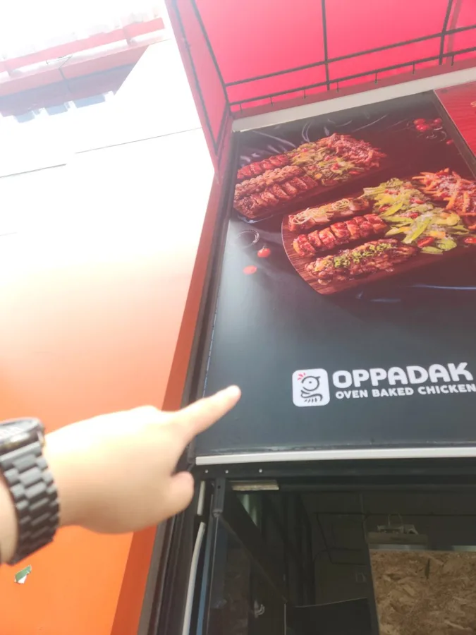상가 간판 아래 위치를 손가락으로 가리키는 모습